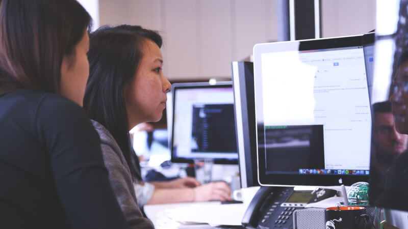 Two women working at a computer to access a database