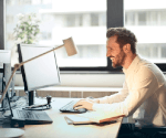 A man sitting at a computer and smiling